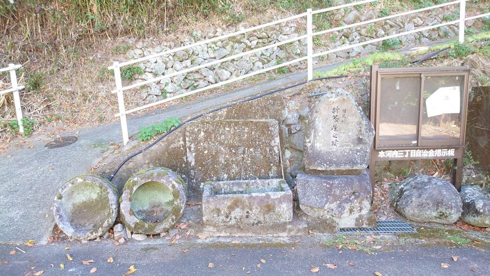 本河内三丁目に残る「日見峠 新茶屋之跡」の碑。石臼二つと石の水槽が並ぶ